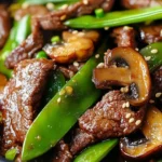 Asian Beef with Mushrooms and Snow Peas dish garnished with fresh herbs