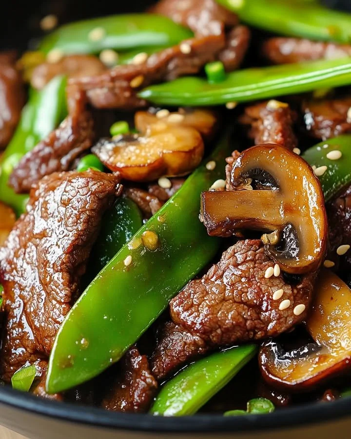 Asian Beef with Mushrooms and Snow Peas dish garnished with fresh herbs