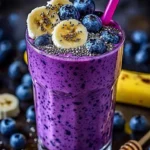 A refreshing Banana-Blueberry Smoothie in a glass with fresh fruits