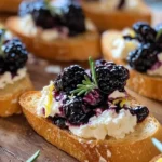 Blackberry goat cheese crostini topped with fresh berries and herbs