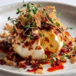 Cracked burrata drizzled with gochujang oil and topped with pistachio brittle