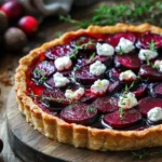 Slice of Cranberry & Roasted Beet Tart on a white plate with fresh herbs