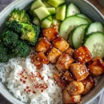 Glazed chicken rice bowl with broccoli and cucumber garnish
