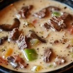 Delicious bowl of Philly cheese steak soup topped with melted cheese and herbs