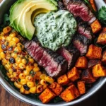 Delicious steak bowl topped with avocado and roasted corn, drizzled with cilantro cream sauce.